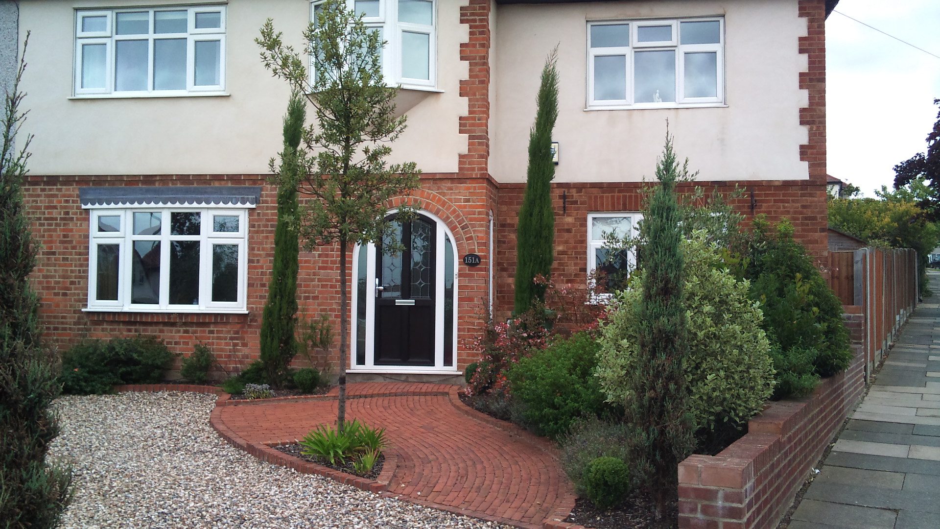 Formal garden with pergola in front of lawn under weeping willow